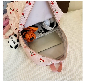 Internal view of pink corduroy cherry backpack showing storage capacity with a panda doll