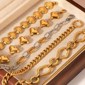 Golden and silver stainless steel heart bracelets showcased in a wooden jewelry box