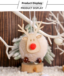 Detail of pink reindeer plush ball ornament with wooden head hanging on a white branch
