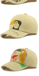 Detailed view of woven straw baseball caps with hand-painted bird and clover motifs