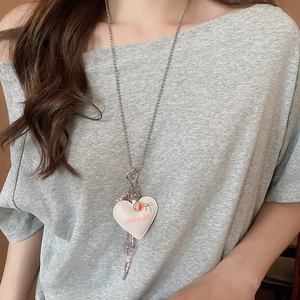 Detail of heart pendant necklace with bow and beetle charms on silver bead chain