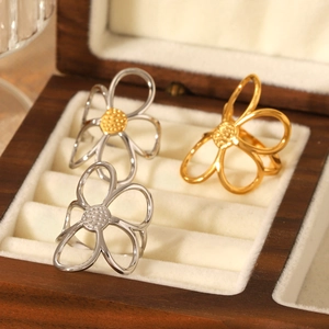 Three hollow flower rings in gold and silver colors displayed on a luxury wooden jewelry box