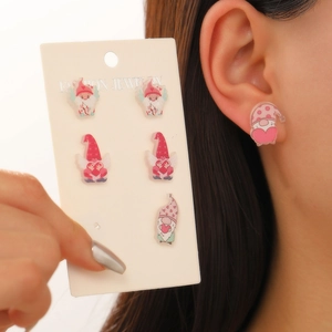 Detail of pink acrylic gnome earrings set on a display card worn by a model
