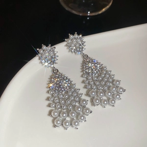 Macro shot of silver drop earrings with white pearls and sparkling rhinestones on ceramic
