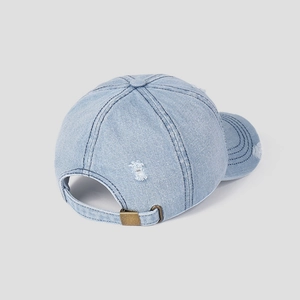 Detailed close-up of distressed denim baseball cap with frayed holes and metal buckle