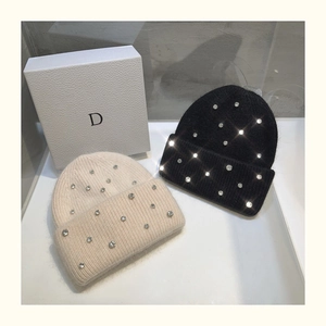 Detailed close-up of beige and black knit beanies with sparkling rhinestone embellishments