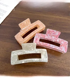 Detailed view of three marble texture acetate hair claws in cream, pink and champagne
