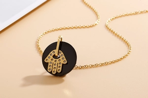 Detailed view of a gold Hamsa Hand pendant with rhinestones on a black circular base