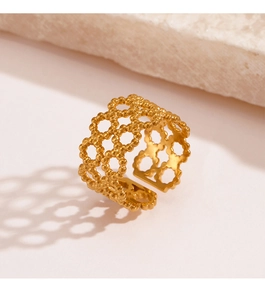 Detailed view of adjustable golden mesh pattern ring with beaded edges on stone background