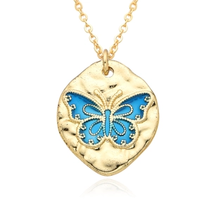 Macro shot of gold butterfly pendant with blue enamel and hammered texture finish