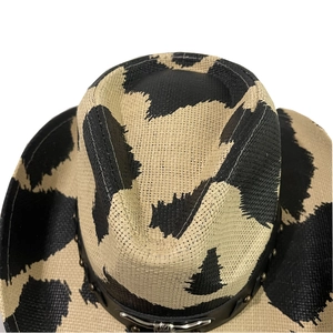 Close-up of cow print straw cowboy hat featuring woven texture and metallic belt detail