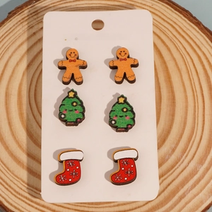 Three pairs of wooden Christmas earrings featuring gingerbread man, tree, and sock shapes