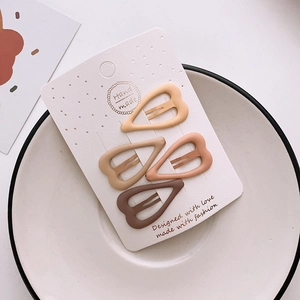 Set of four heart-shaped matte hair clips in brown and yellow tones on display card