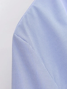 Close-up of sewing craftsmanship and fabric texture on blue striped poplin shirt