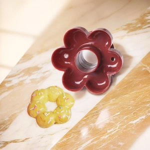 Flower shaped plastic donut mold with finished colorful doughnut on marble surface