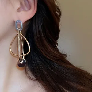 Boucles d'oreilles géométriques argentées et dorées portées par un mannequin