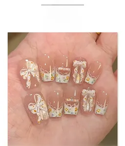 Close-up of pink cat eye press-on nails with 3D white bows and floral patterns