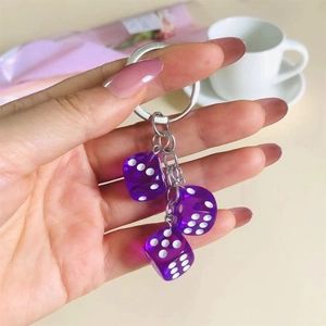 Close-up of hand holding creative purple resin dice charms on a metal keychain
