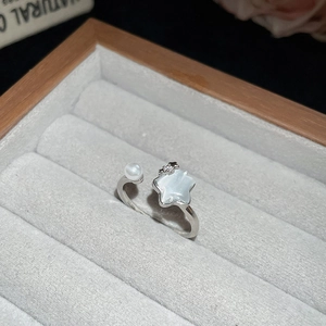 Detailed shot of silver open ring with white star charm and pearl in a velvet jewelry box
