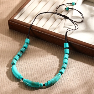 Detail of turquoise beaded necklace with adjustable brown woven cord on wooden display