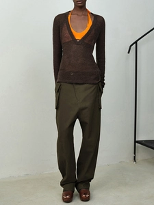 Women's orange halter top layered with sheer brown knit vest and olive cargo pants