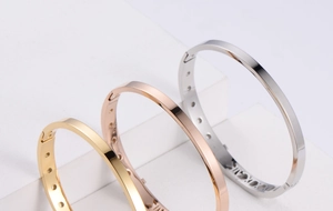 Detailed view of hollow cut-out bangles with Roman numerals in gold, rose gold and silver