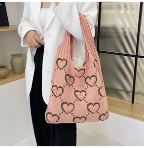Détail du sac tricoté rose avec motif cœur vert et texture de maille douce