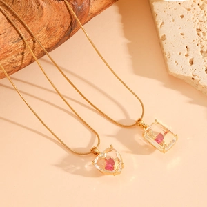 Détail de pendentifs cœur rose en verre sur chaînes serpent en acier inoxydable doré