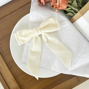 Elegant cream velvet bow hair clip with long ribbons on a decorative display