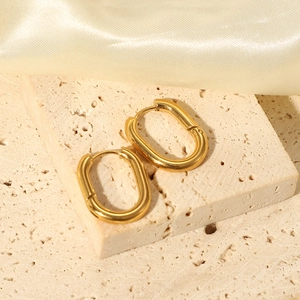 Detailed view of gold-plated U-shaped earrings on stone surface with silk background