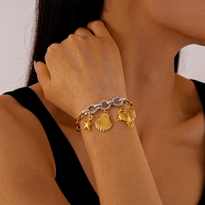 Detail of gold and silver chain bracelet featuring starfish shell and crab charms