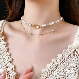 Close-up of a double-layered gold necklace with pearls and clear crystal pendant
