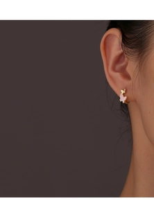Detail of pink butterfly hoop earrings worn on ear with elegant gold finish design