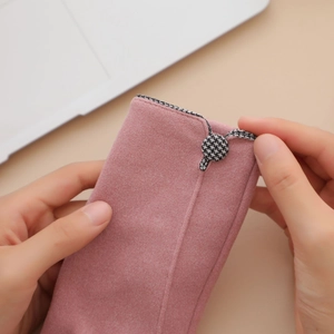 Close-up of pink velvet gloves with houndstooth button detail and touchscreen feature