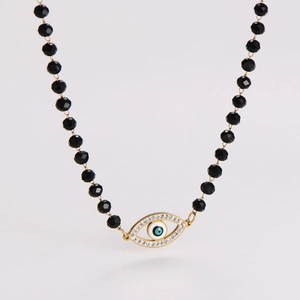 Detailed close-up of a beaded necklace with a golden evil eye pendant and sparkling rhinestones