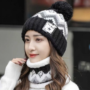Detailed knit texture of a black and grey winter beanie and scarf set with pom poms