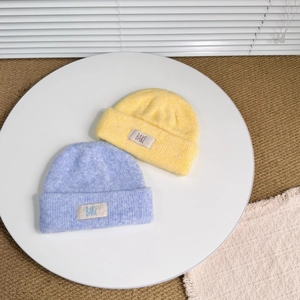 Detailed knit texture of thick wool winter beanies in purple and yellow with fabric label