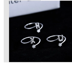 Macro shot of silver open rings with zircon letters H X U and a solitaire diamond detail
