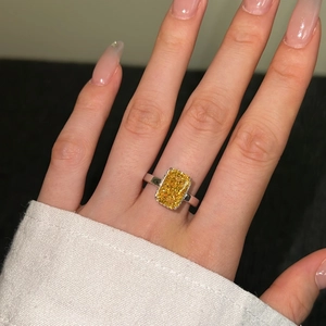 Macro shot of a rectangular yellow ice-cut gemstone ring on a finger with silver band