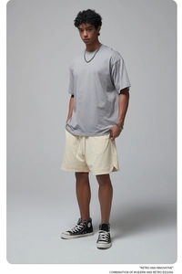 Full view of oversized grey cotton T-shirt paired with beige shorts and high-top sneakers