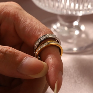 Close-up of sparkling gold and silver titanium steel rings with cubic zirconia on finger