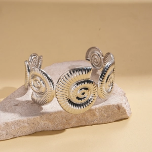 Close-up of silver nautilus spiral cuff bracelet on stone base with textured details