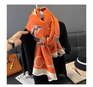 Detailed view of orange horsebit pattern scarf with soft fringe trim and thick wool texture