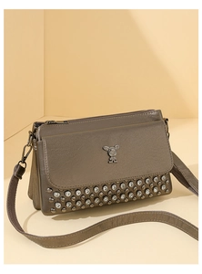 Detail of brown leather crossbody bag with rabbit buckle, rivets and rhinestones