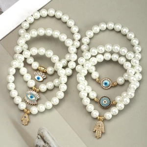 Woven pearl bracelet set with golden evil eye and hamsa hand charms for women