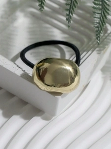 Close-up of minimalist gold irregular metal block on a black elastic hair tie