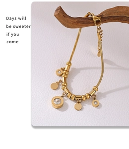 Detail of gold snake chain necklace with Roman numeral charms and sparkling zircon inlays