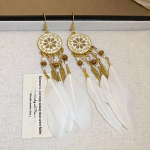 Detailed macro view of bohemian long earrings with white feathers and gold floral discs