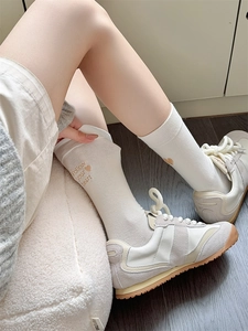 Detail showing white crew socks with Follow your heart embroidery and heart pattern