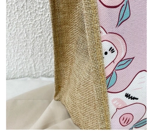 Close-up of jute tote bag showing coarse fiber texture and cute peach cartoon print